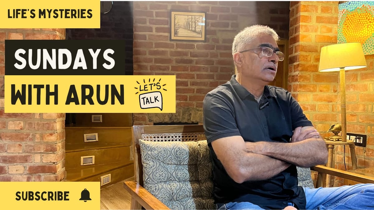 Sundays with Arun episode thumbnail — Arun Pandala sitting back on a wooden sofa in a dark polo shirt, arms folded, a lit floor lamp beside him