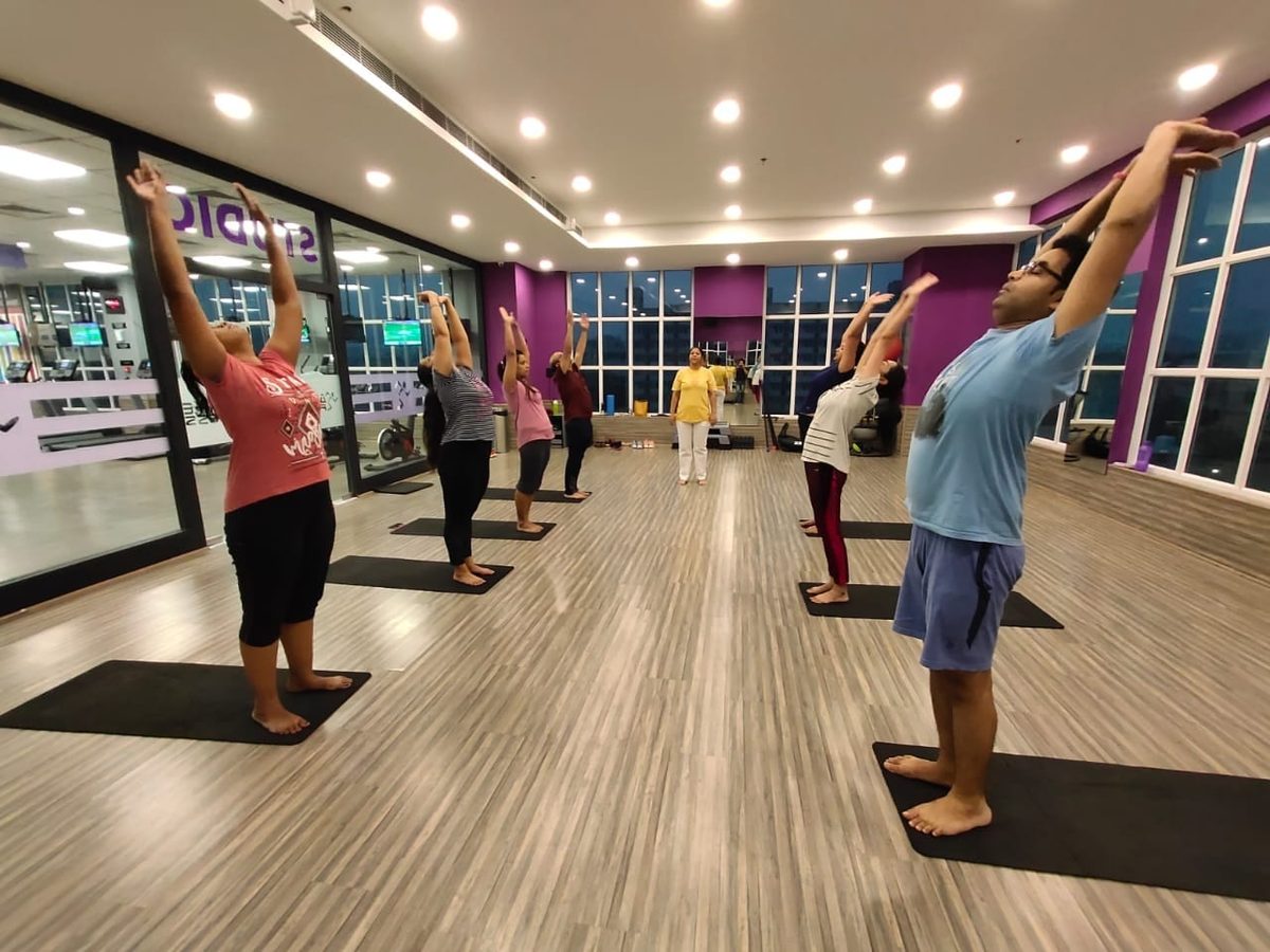 A standing back bend in a studio class, arms overhead