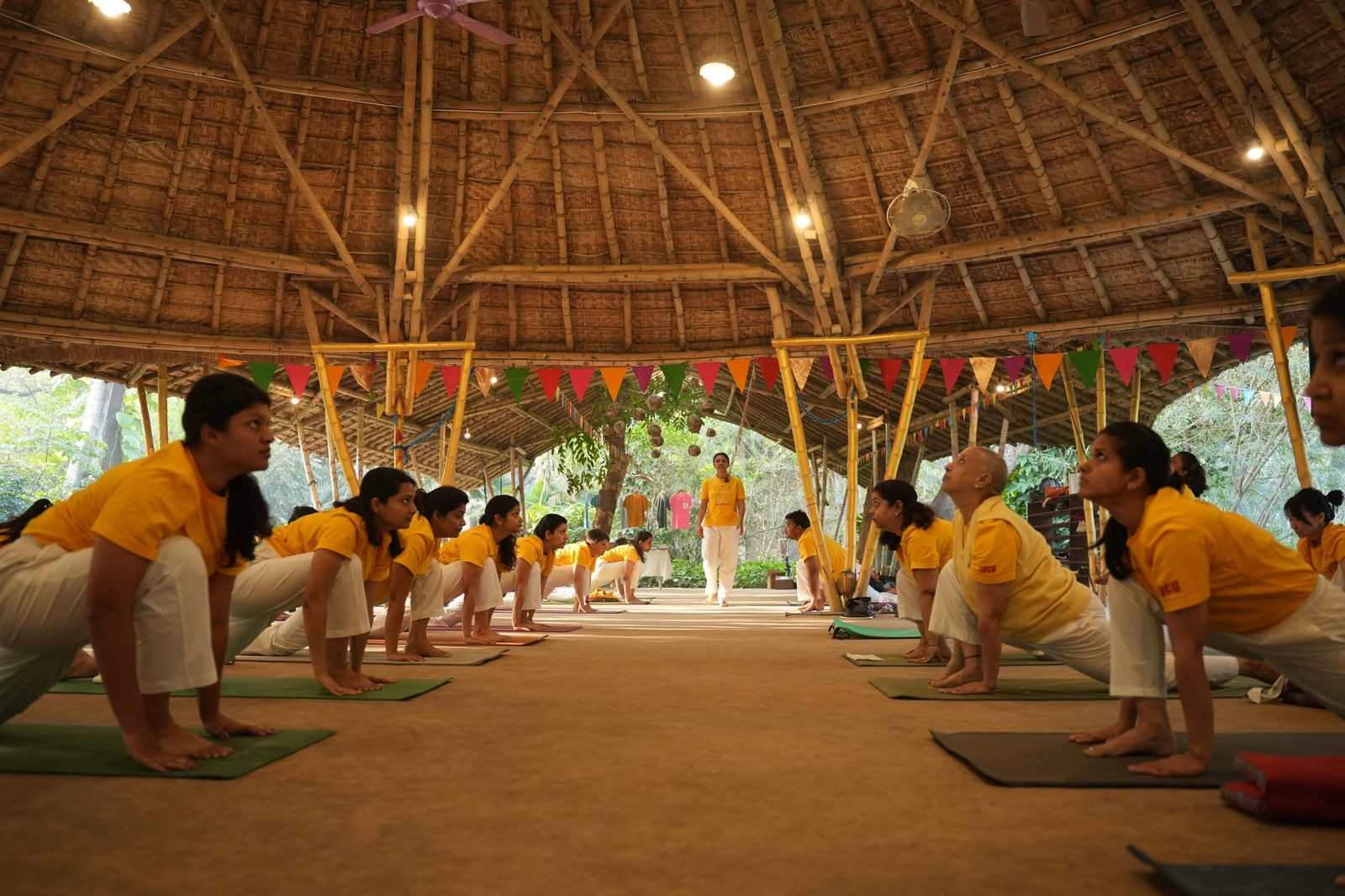 A class practicing together under the thatched pavilion at a Sivananda Gurgaon retreat.