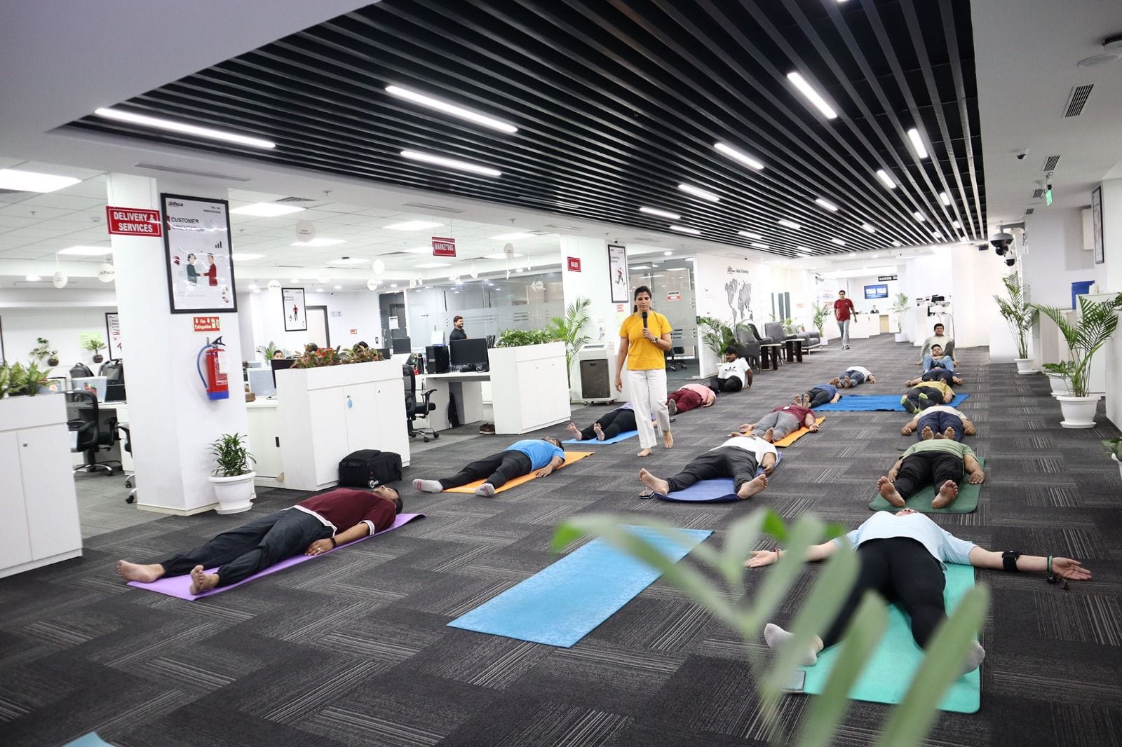 Staff lying in relaxation on mats on the open floor of a carpeted office