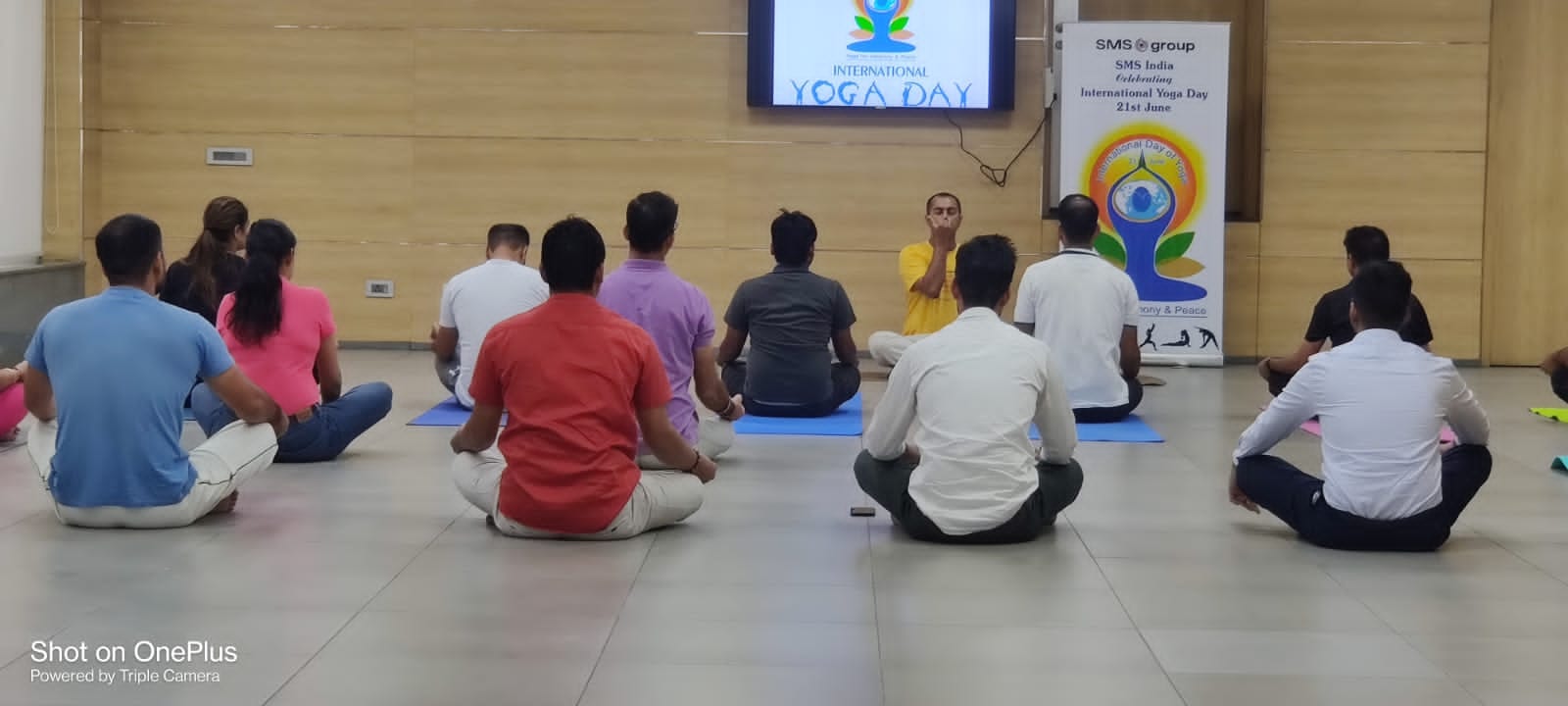 An International Yoga Day session, participants seated cross-legged before a teacher