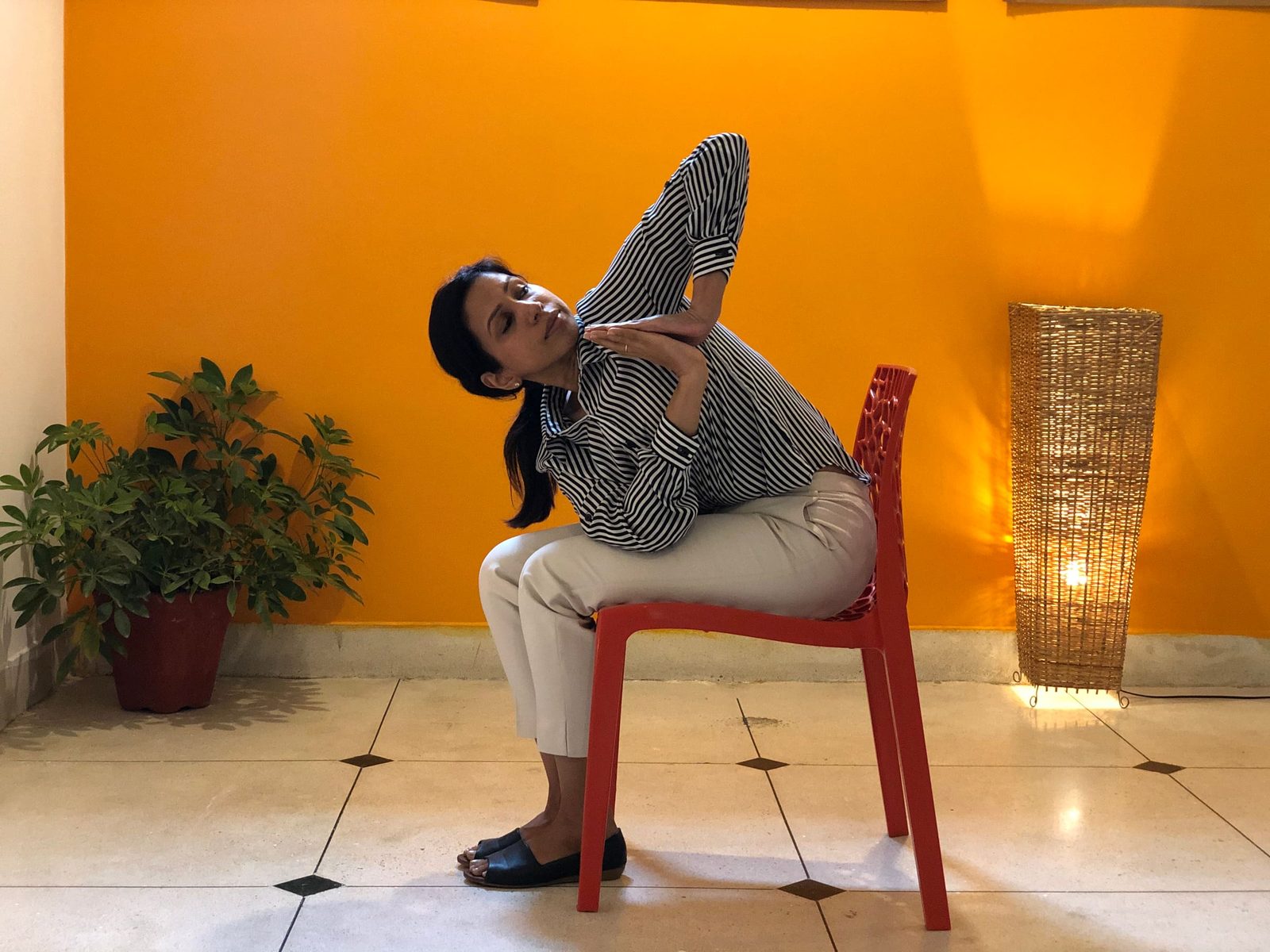 A seated spinal twist done on a plastic chair