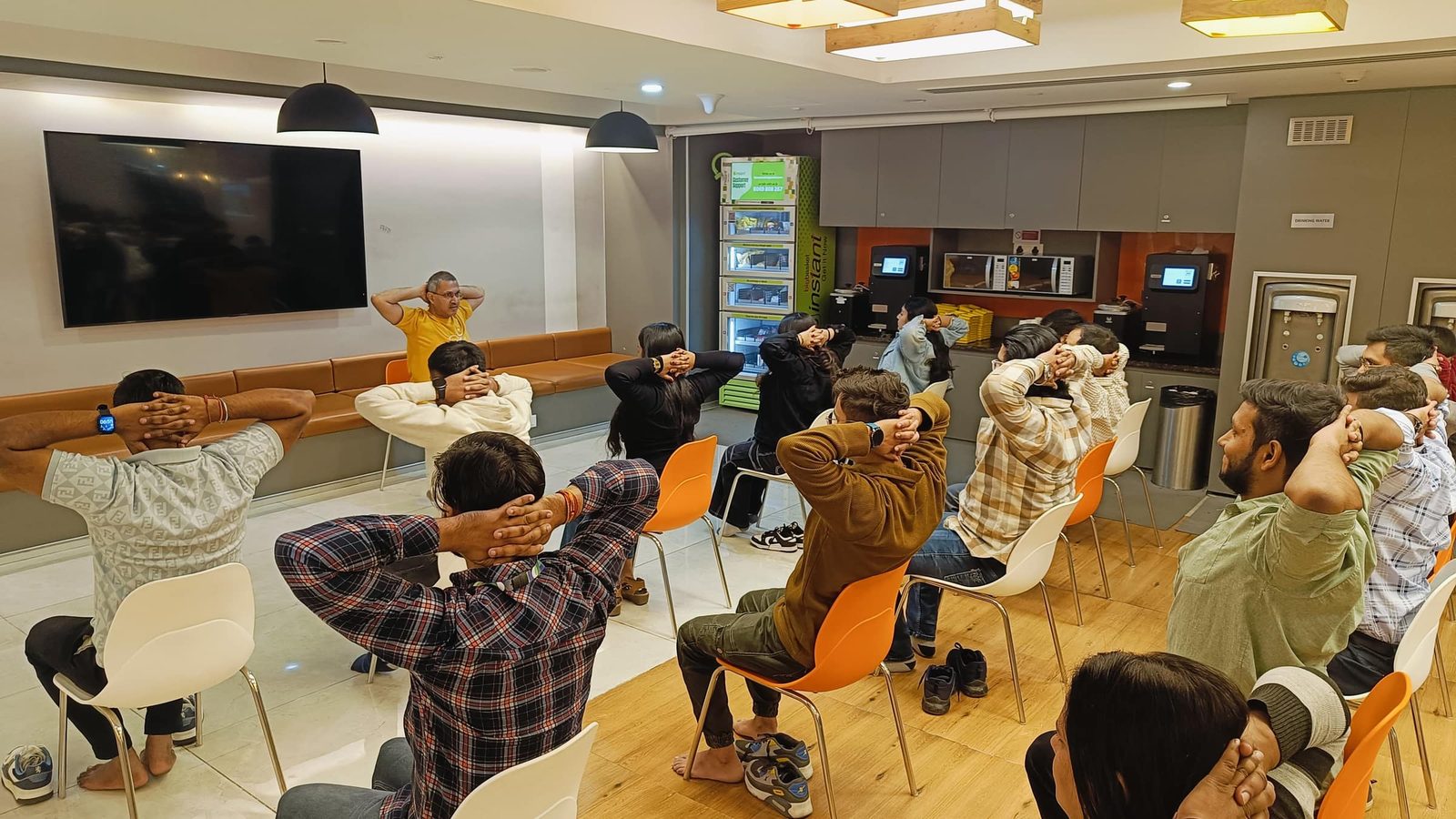 An office lounge session, staff seated on chairs with hands behind the head