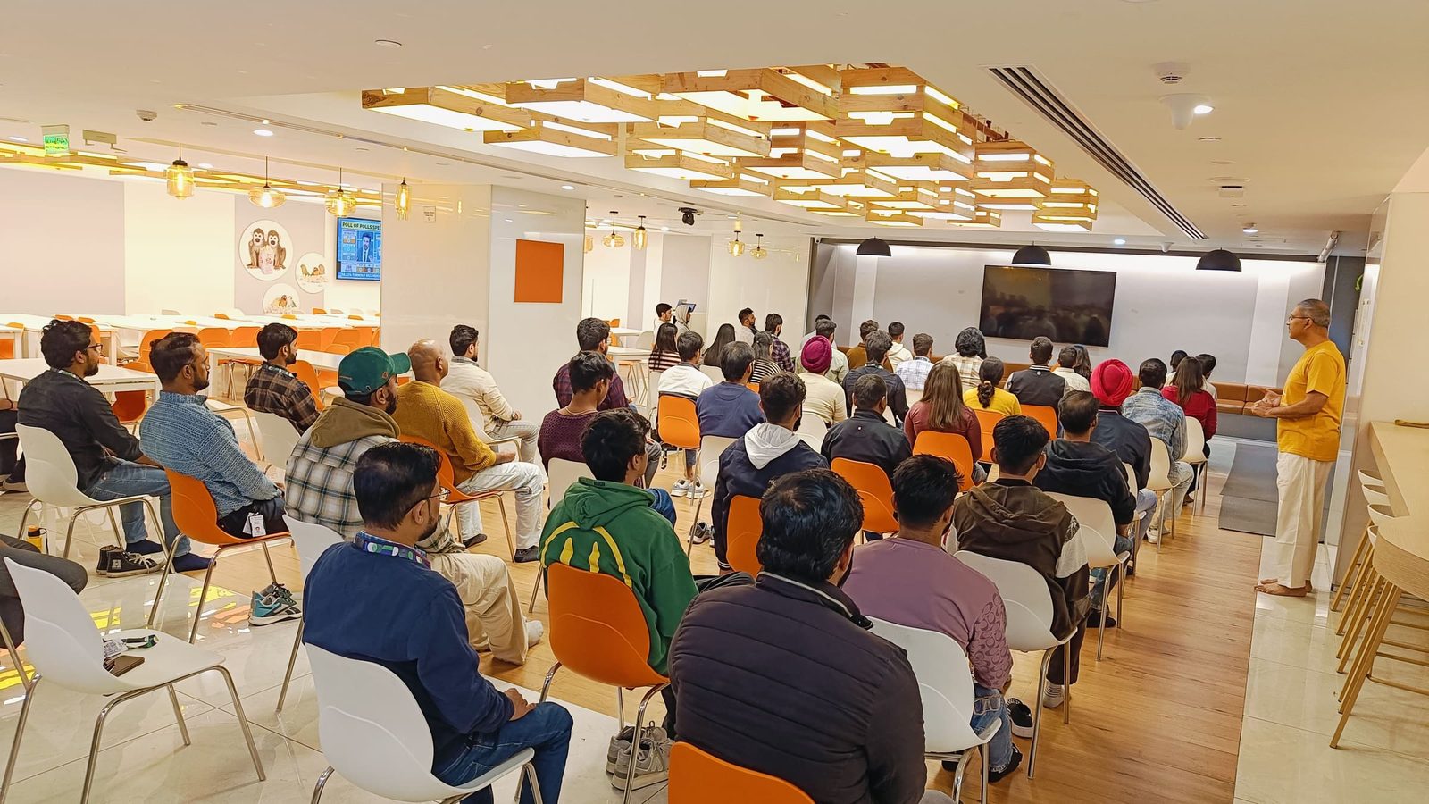 A teacher speaking to seated staff in an office café