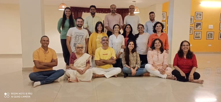 A group of Sivananda Gurgaon teachers posed together in the hall, two rows standing behind a front row seated cross-legged on the floor