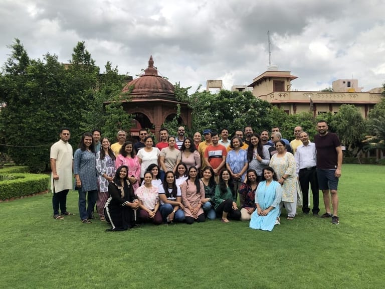 A Sivananda Gurgaon retreat group gathered for a photograph on the lawn, in front of a domed stone pavilion.