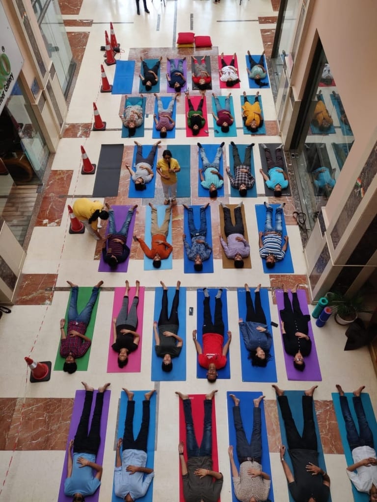 An office atrium seen from above, rows of staff lying in relaxation on coloured mats