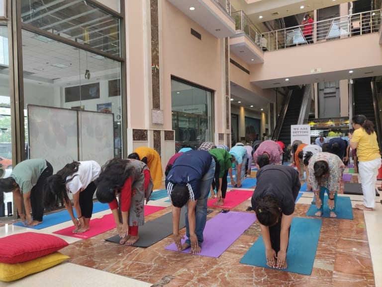 A standing forward fold practiced on mats in an office lobby
